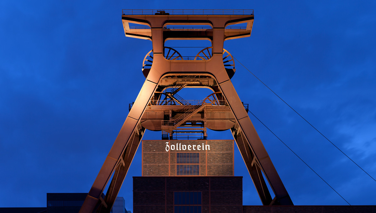 Wahrzeichen der Stadt Essen, die Zeche Zollverein (Foto © Thomas Wolf, www.foto-tw.de. Lizenz CC BY-SA 3.0 DE. https://de.wikipedia.org/wiki/Essen#/media/File:Zeche_Zollverein_abends.jpg).